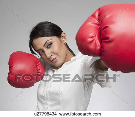 Picture - Businesswoman punching with boxing gloves. Fotosearch