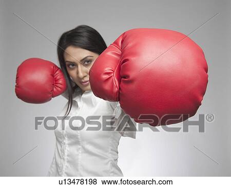 Businesswoman punching with boxing gloves View Large Photo Image Stock Photo - Businesswoman punching with boxing gloves. Fotosearch