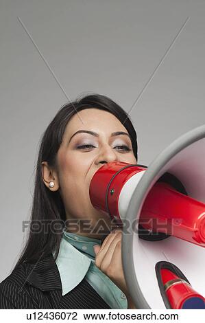 Stock Image - Businesswoman shouting into a megaphone. Fotosearch