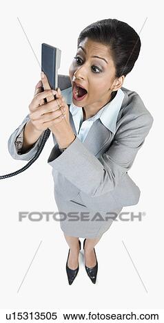 Stock Photography - Businesswoman shouting into a telephone receiver. Fotosearch
