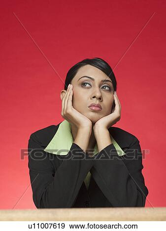 Businesswoman sitting at a table and thinking View Large Photo Image Stock Photo - Businesswoman sitting at a table and thinking. Fotosearch