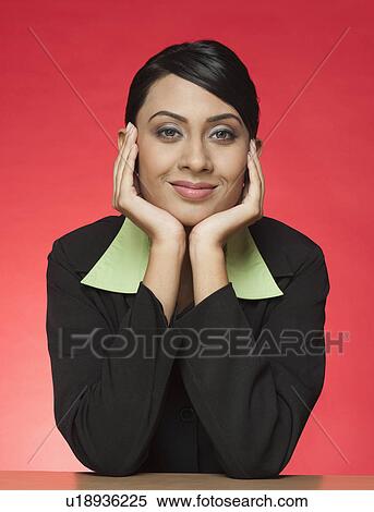 Businesswoman sitting at a table and smiling View Large Photo Image Stock Photography - Businesswoman sitting at a table and smiling. Fotosearch