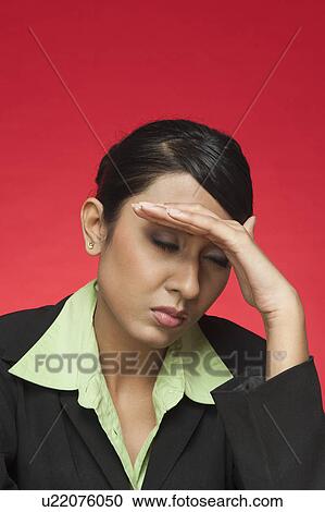 Stock Image - Businesswoman suffering from a headache. Fotosearch