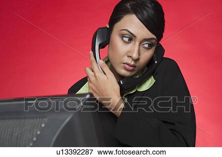 Businesswoman talking on multiple landline phones View Large Photo Image Stock Photo - Businesswoman talking on multiple landline phones. Fotosearch