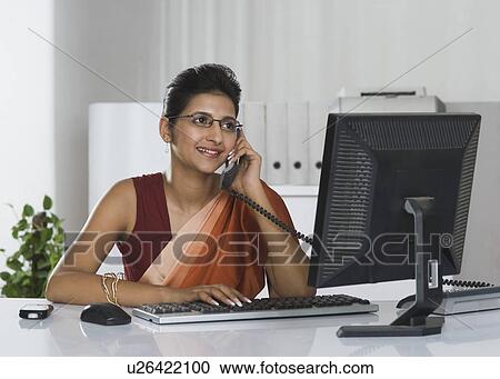 Stock Image - Businesswoman talking on the telephone in an office. Fotosearch