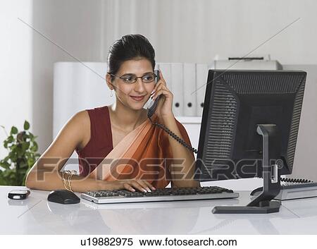 Stock Photography - Businesswoman talking on the telephone in an office. Fotosearch