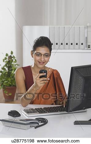 Stock Photo - Businesswoman text messaging on a mobile phone. Fotosearch