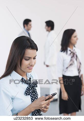 Businesswoman text messaging with a mobile phone View Large Photo Image Stock Image - Businesswoman text messaging with a mobile phone. Fotosearch