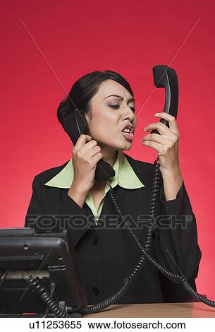 Businesswoman using multiple landline phones and shouting View Large Photo Image Stock Photography - Businesswoman using multiple landline phones and shouting. Fotosearch