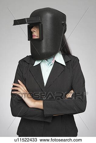Stock Image - Businesswoman wearing a welding mask. Fotosearch