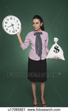 Stock Image - Businesswoman weighing time versus money. Fotosearch