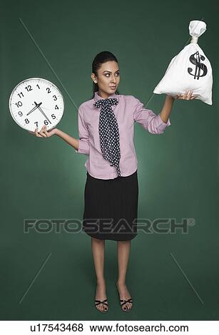 Businesswoman weighing time versus money View Large Photo Image Stock Photo - Businesswoman weighing time versus money. Fotosearch
