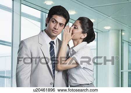 Stock Photograph - Businesswoman whispering to a businessman. Fotosearch