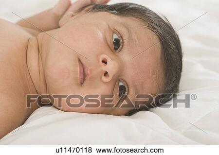Close-up of a baby lying on the bed View Large Photo Image Stock Photo - Close-up of a baby lying on the bed. Fotosearch
