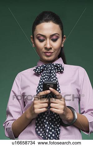 Picture - Close-up of a businesswoman text messaging on a mobile phone. Fotosearch