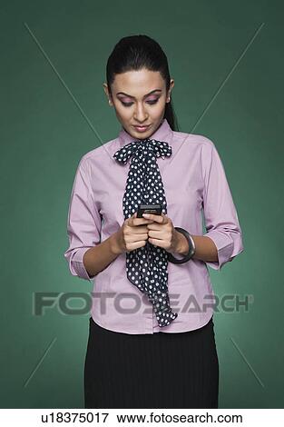 Stock Photo - Close-up of a businesswoman text messaging on a mobile phone. Fotosearch