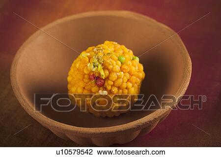 Stock Image - Close-up of a motichoor laddoo (a popular traditional Indian sweet) in a bowl. Fotosearch