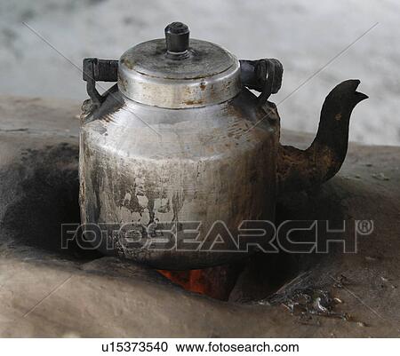 Stock Image - Close-up of a tea kettle on a mud stove. Fotosearch