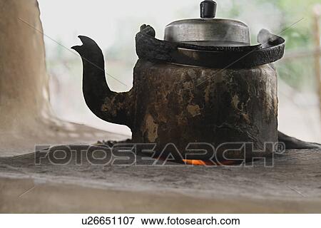 Stock Photo - Close-up of a tea kettle on a mud stove. Fotosearch