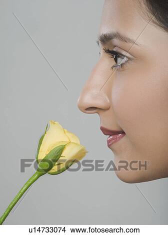 Picture - Close-up of a woman smelling a flower. Fotosearch
