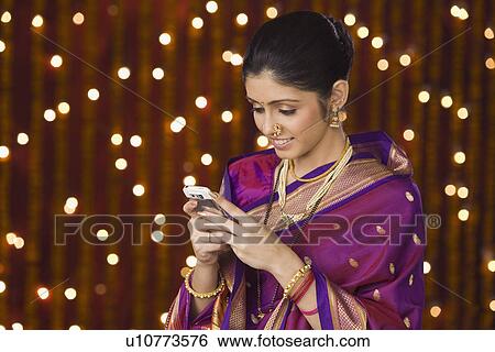 Stock Photograph - Close-up of a woman smiling in front of Diwali decoration. Fotosearch