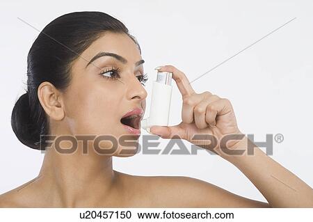 Stock Image - Close-up of a woman using an asthma inhaler. Fotosearch