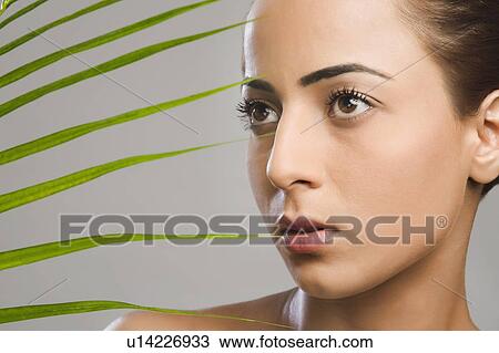 Stock Image - Close-up of a woman with palm leaves. Fotosearch