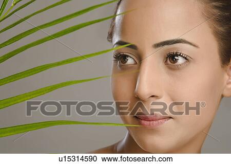 Stock Image - Close-up of a woman with palm leaves. Fotosearch