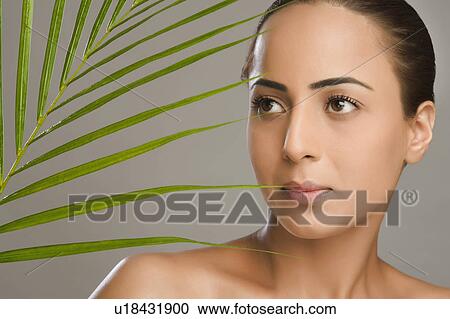 Stock Image - Close-up of a woman with palm leaves. Fotosearch