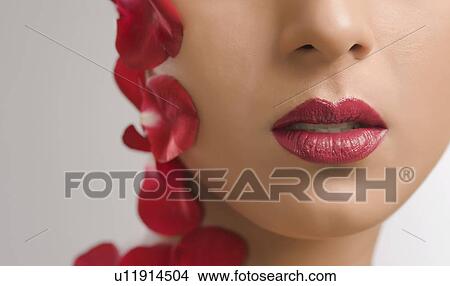 Picture - Close-up of a woman with rose petals on her face. Fotosearch