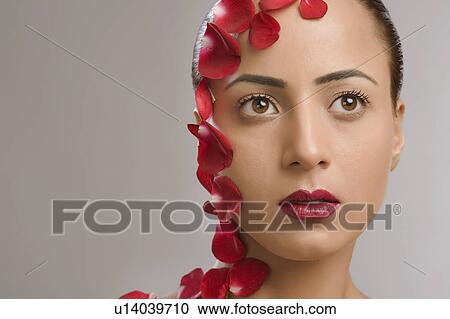 Stock Image - Close-up of a woman with rose petals on her face. Fotosearch