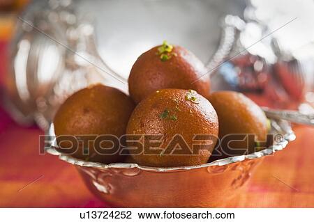 Stock Image - Close-up of gulab jamuns (a popular traditional Indian sweet) in a bowl. Fotosearch