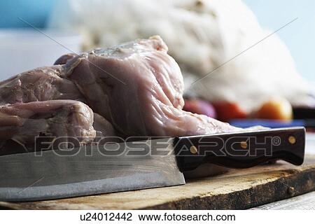 Stock Image - Close-up of raw chicken with a knife. Fotosearch