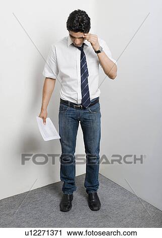 Stock Image - College student standing in the corner looking worried. Fotosearch