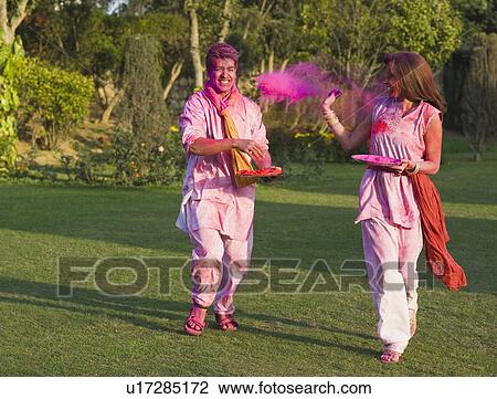 Stock Image - Couple celebrating Holi in a garden. Fotosearch