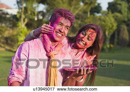 Stock Photo - Couple celebrating Holi in a garden. Fotosearch