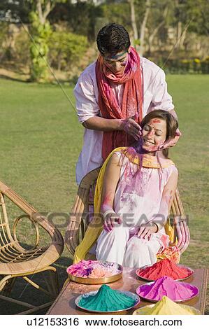 Stock Photograph - Couple celebrating Holi in a garden. Fotosearch