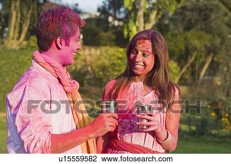 Stock Image - Couple celebrating Holi with glass of bhang. Fotosearch