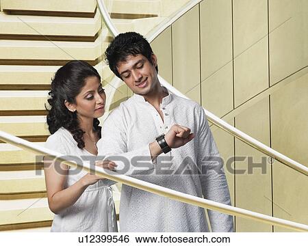Stock Photograph - Couple checking the time on a staircase. Fotosearch