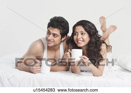 Stock Image - Couple drinking coffee on the bed. Fotosearch