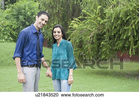 Couple enjoying rain in a park View Large Photo Image Stock Image - Couple enjoying rain in a park. Fotosearch