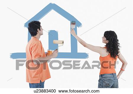 Stock Image - Couple painting a model home on the wall. Fotosearch