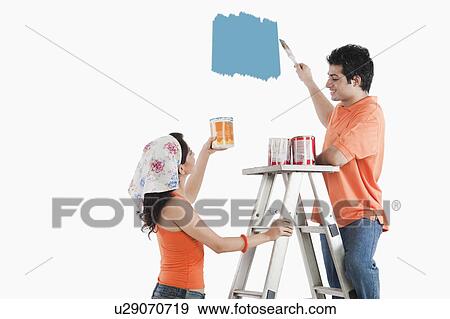 Couple painting the wall of a house View Large Photo Image Stock Photo - Couple painting the wall of a house. Fotosearch