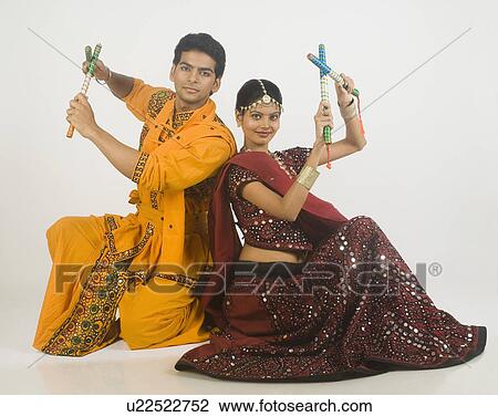 Stock Image - Couple performing dandiya. Fotosearch