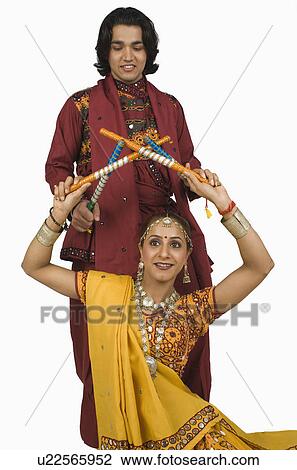 Stock Image - Couple performing dandiya. Fotosearch