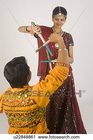 Stock Image - Couple performing dandiya. Fotosearch