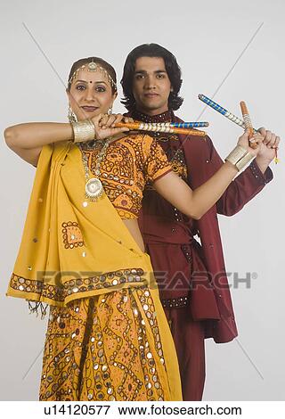 Couple performing dandiya View Large Photo Image Stock Photo - Couple performing dandiya. Fotosearch