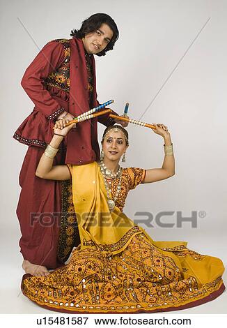 Couple performing dandiya View Large Photo Image Stock Photo - Couple performing dandiya. Fotosearch