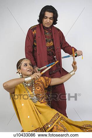 Couple performing dandiya View Large Photo Image Stock Photograph - Couple performing dandiya. Fotosearch