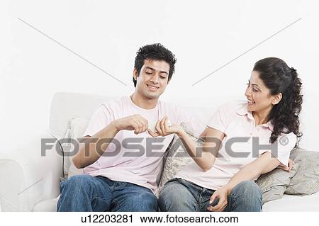 Stock Image - Couple playing with a remote control on a couch. Fotosearch